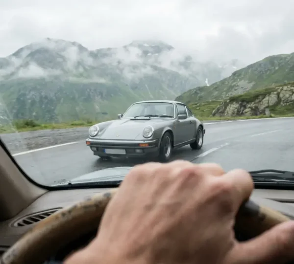 Porsche 911 grise en mouvement sur route de montagne sinueuse