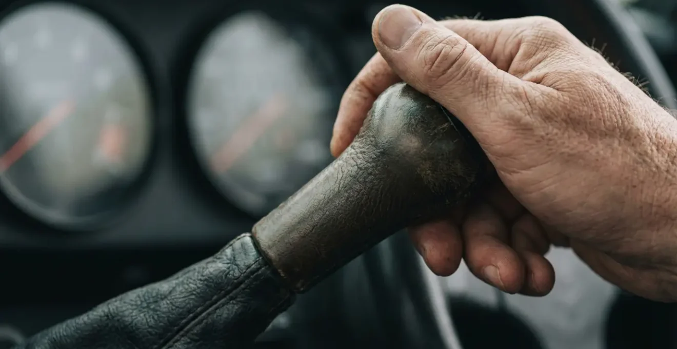 Main sur levier de vitesse avec tableau de bord montrant une conduite économique